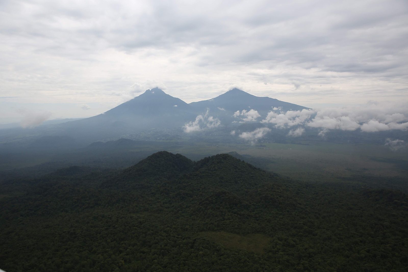 Virunga volcanoes emerging from cloud above cultivated foothills